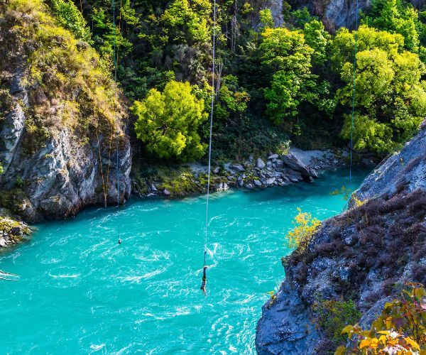 Man hanging by a bungy rope over a river