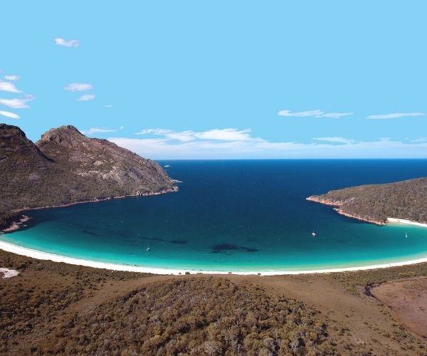 Blue water, white sand beach surrounded by mountain